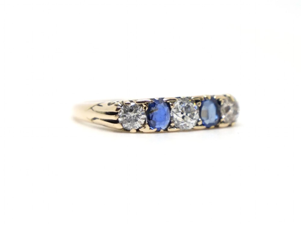 An 18ct yellow gold five-stone ring set with alternating round diamonds and oval blue sapphires in claw mounts. View II
