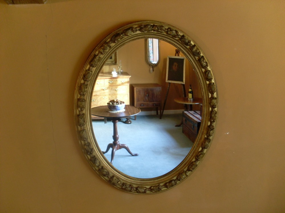 A grand gilded Victorian oval wall mirror