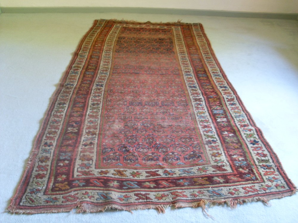 An antique rug 298 cms x 134 cms