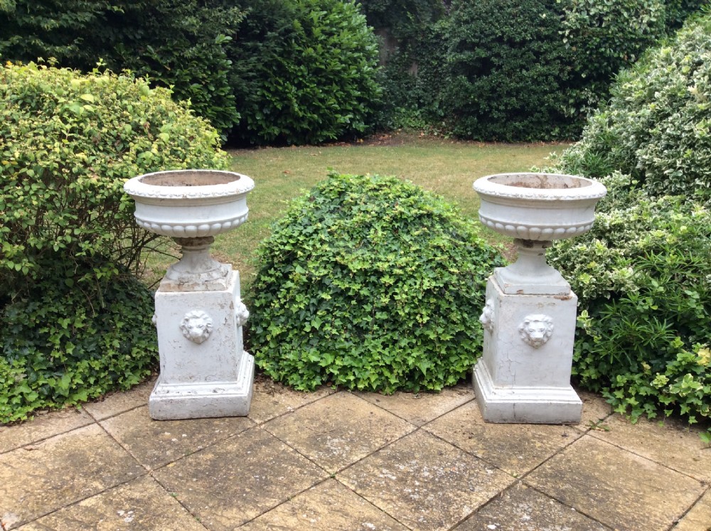 A pair of white painted 19th-century cast iron garden urns featuring gadrooned basins set upon square pedestals with lion head relief motifs. View III