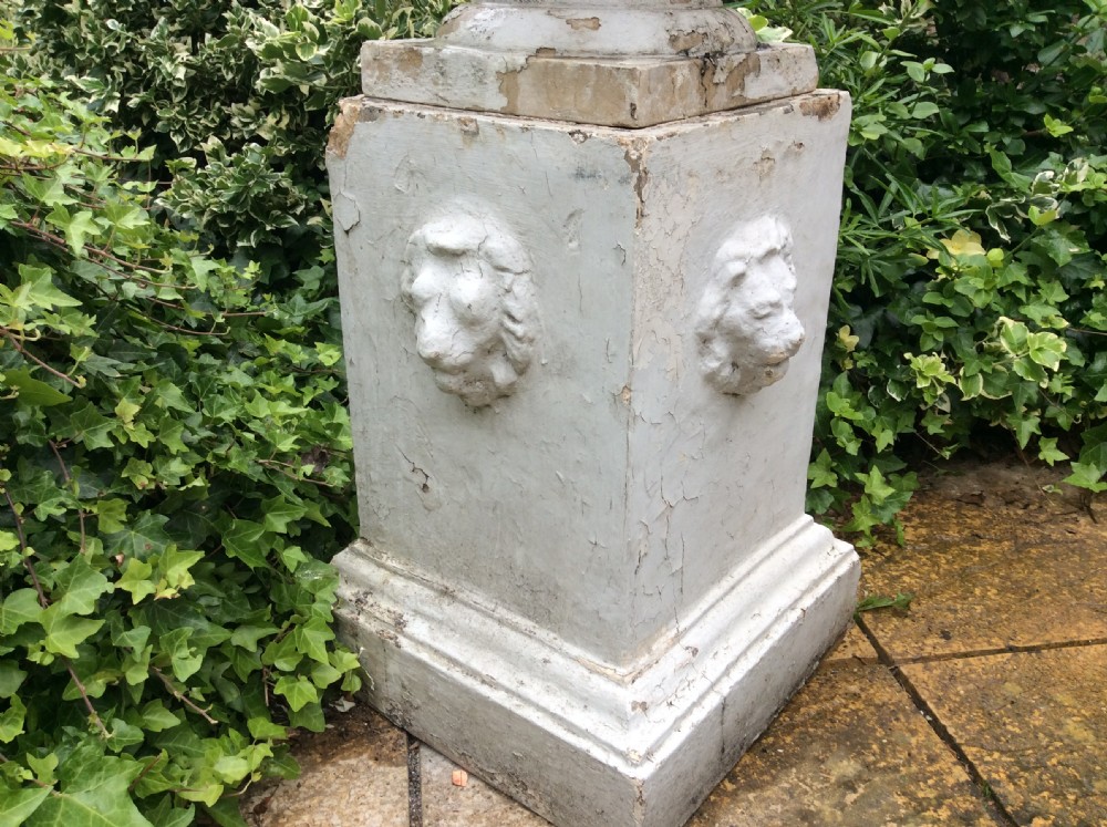 A pair of white painted 19th-century cast iron garden urns featuring gadrooned basins set upon square pedestals with lion head relief motifs. View IX