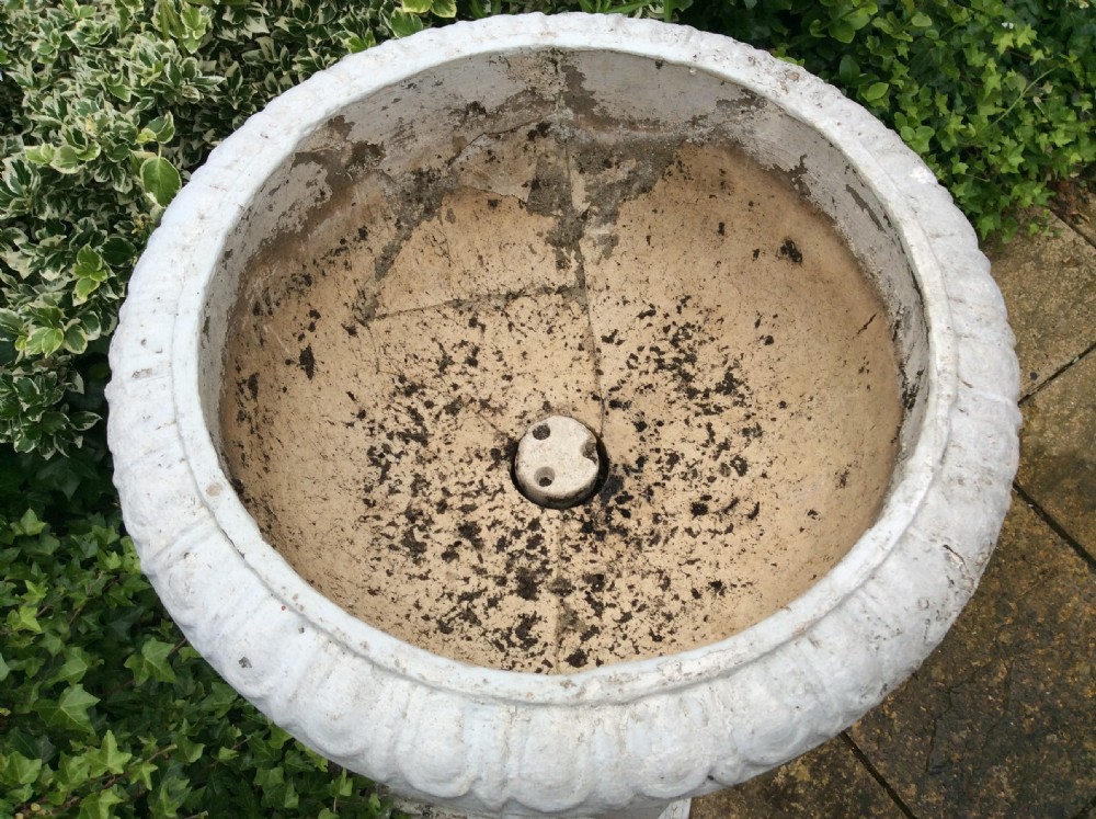 A pair of white painted 19th-century cast iron garden urns featuring gadrooned basins set upon square pedestals with lion head relief motifs. View X