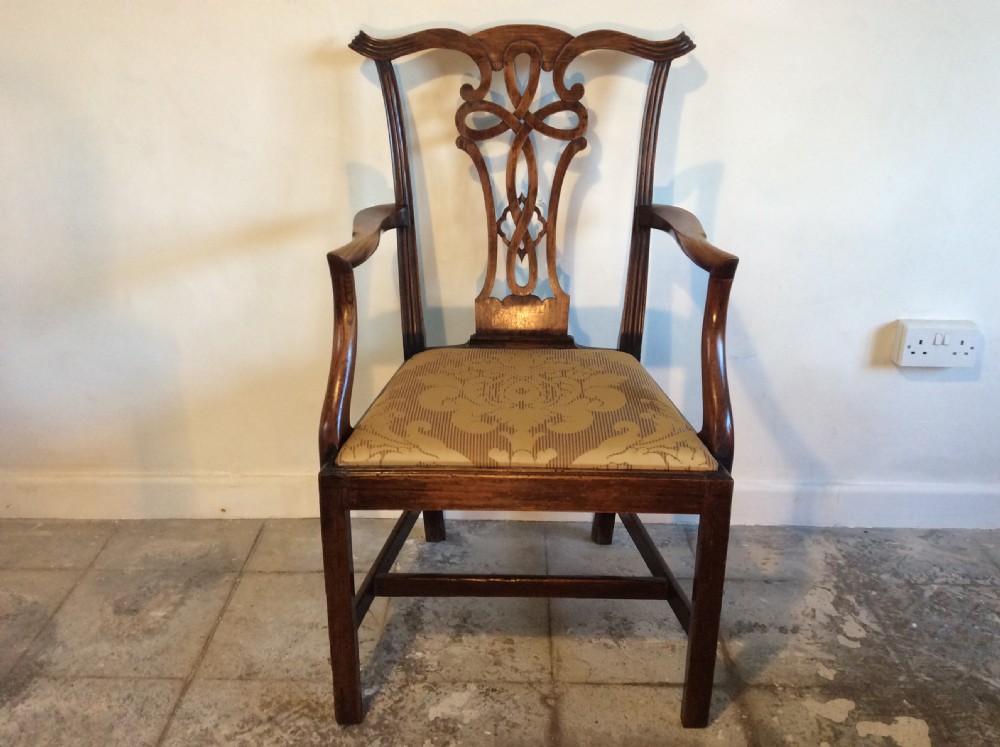 A Georgian George III elm open armchair featuring a pierced strapwork splat back, curved armrests, and a patterned upholstered seat.