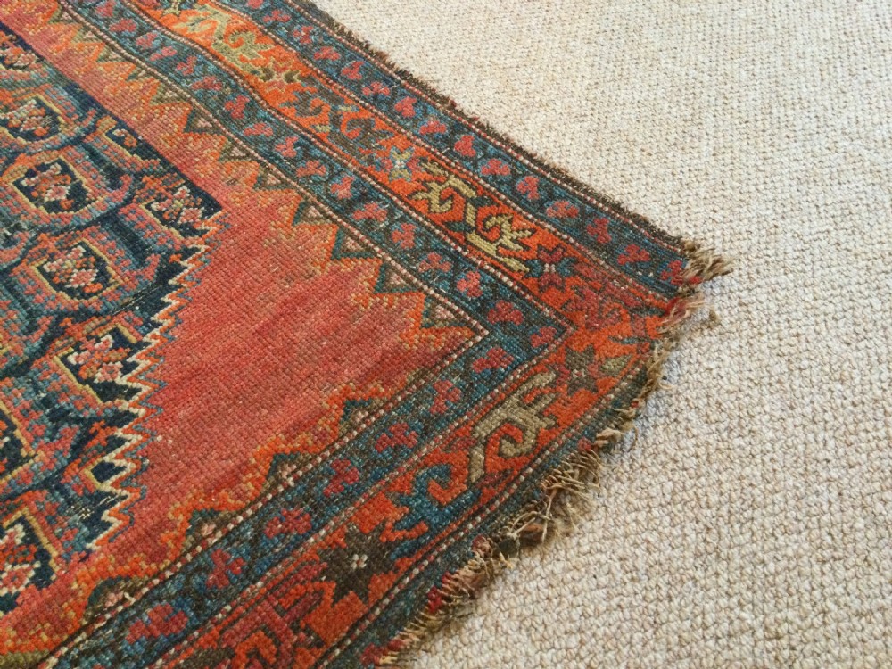 An antique hand-knotted Caucasian prayer rug displaying a central mihrab arch and repeating geometric motifs in terracotta, indigo, and navy wool. View III