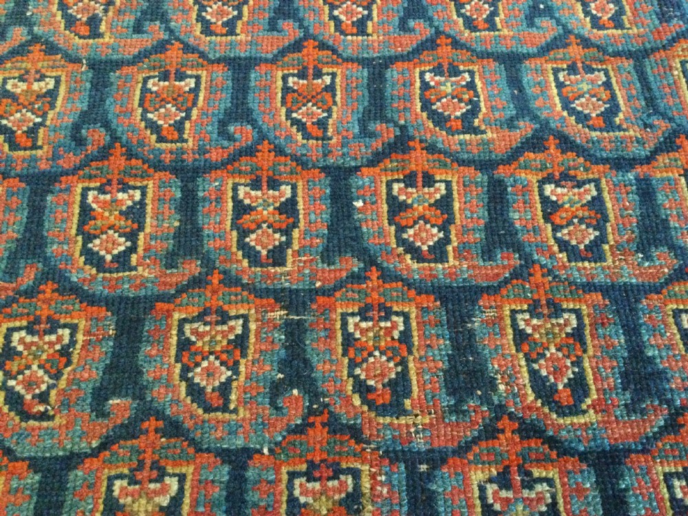 An antique hand-knotted Caucasian prayer rug displaying a central mihrab arch and repeating geometric motifs in terracotta, indigo, and navy wool. View V