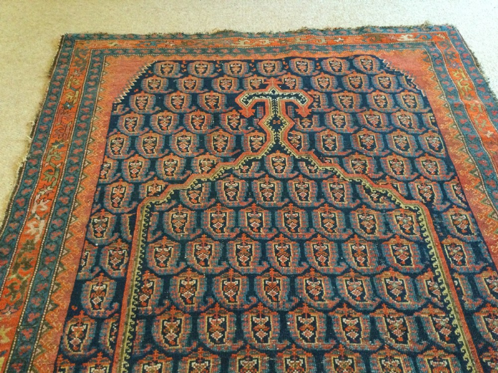 An antique hand-knotted Caucasian prayer rug displaying a central mihrab arch and repeating geometric motifs in terracotta, indigo, and navy wool. View VI