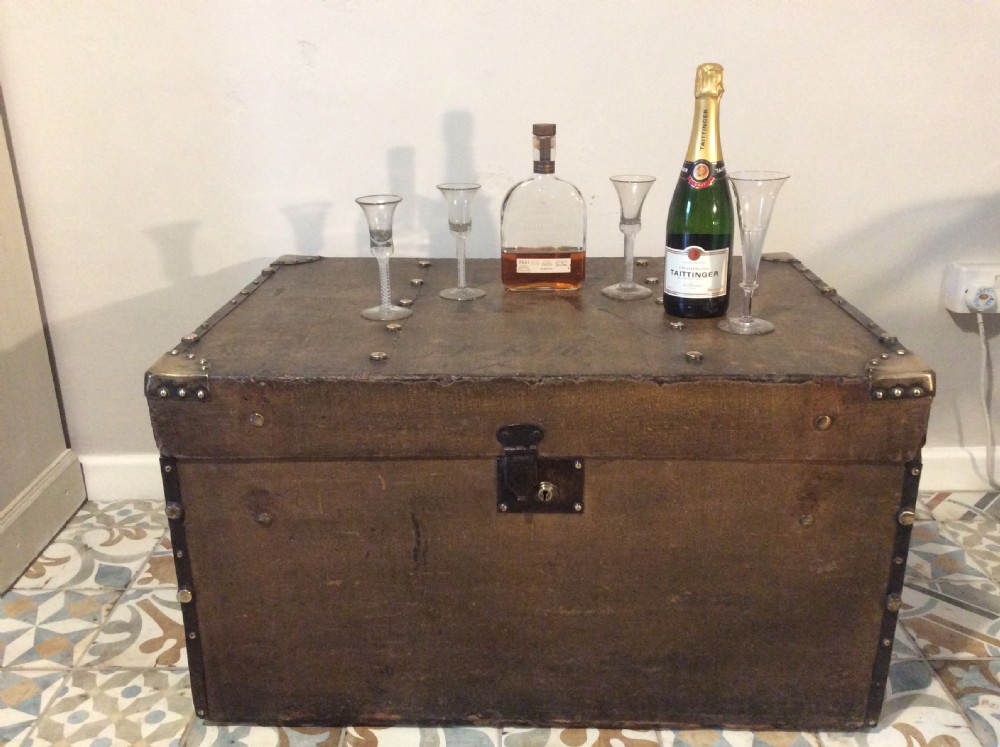 A rectangular Victorian dark brown canvas-covered trunk featuring brass corner caps, brass studs, a central lock, and stencilled black initials on the flat lid. View II