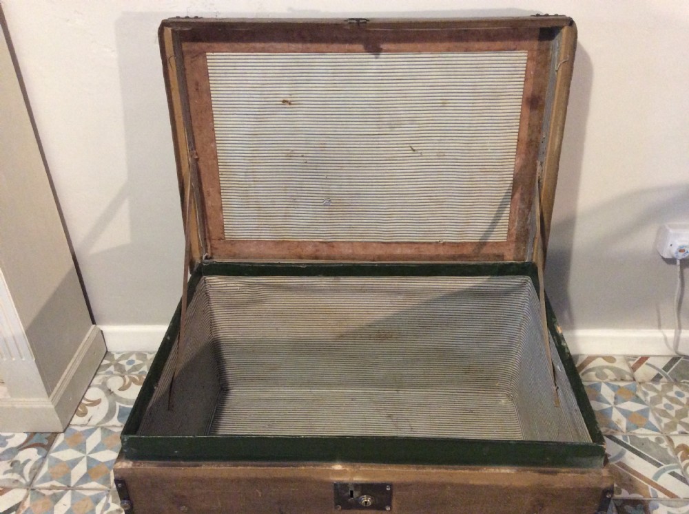 A rectangular Victorian dark brown canvas-covered trunk featuring brass corner caps, brass studs, a central lock, and stencilled black initials on the flat lid. View XIX