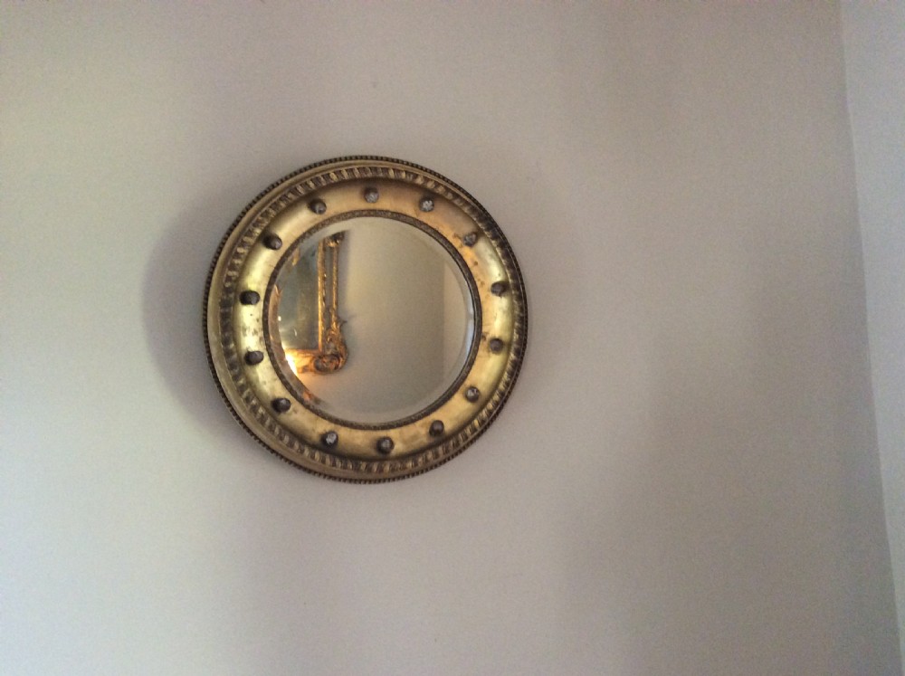 A 19th-century circular convex mirror featuring a gilded frame with decorative spherule accents.