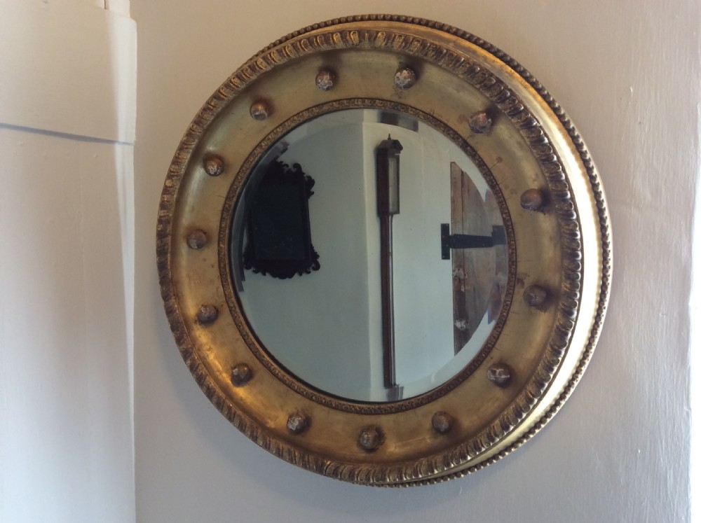 A 19th-century circular convex mirror featuring a gilded frame with decorative spherule accents. View III
