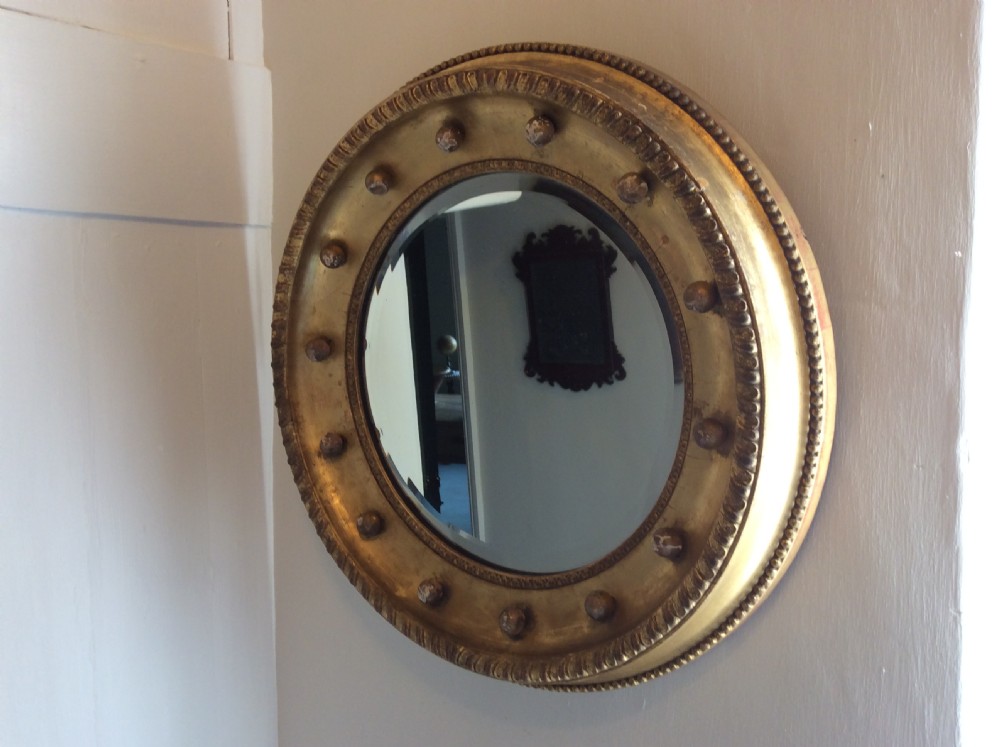 A 19th-century circular convex mirror featuring a gilded frame with decorative spherule accents. View IV