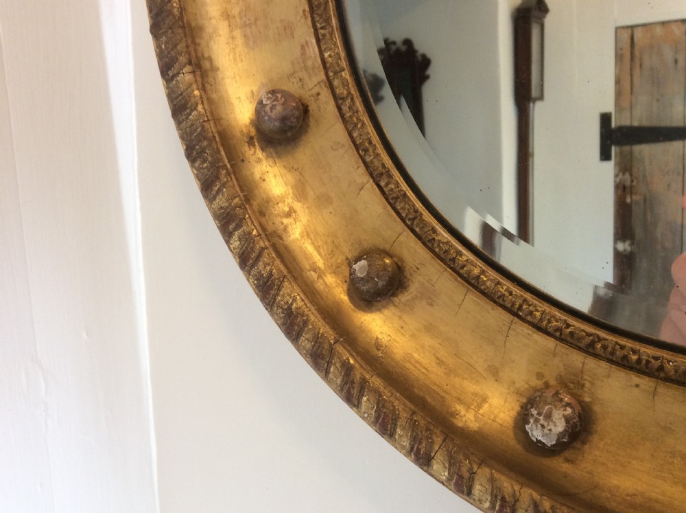 A 19th-century circular convex mirror featuring a gilded frame with decorative spherule accents. View V