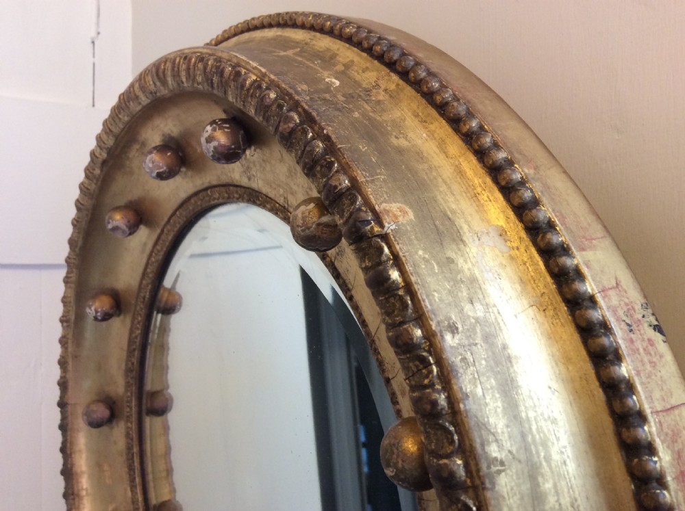 A 19th-century circular convex mirror featuring a gilded frame with decorative spherule accents. View VI