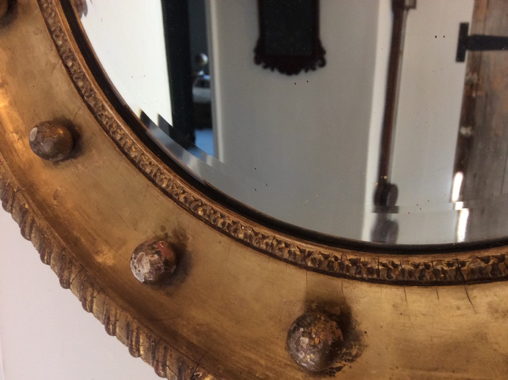 A 19th-century circular convex mirror featuring a gilded frame with decorative spherule accents. View VII