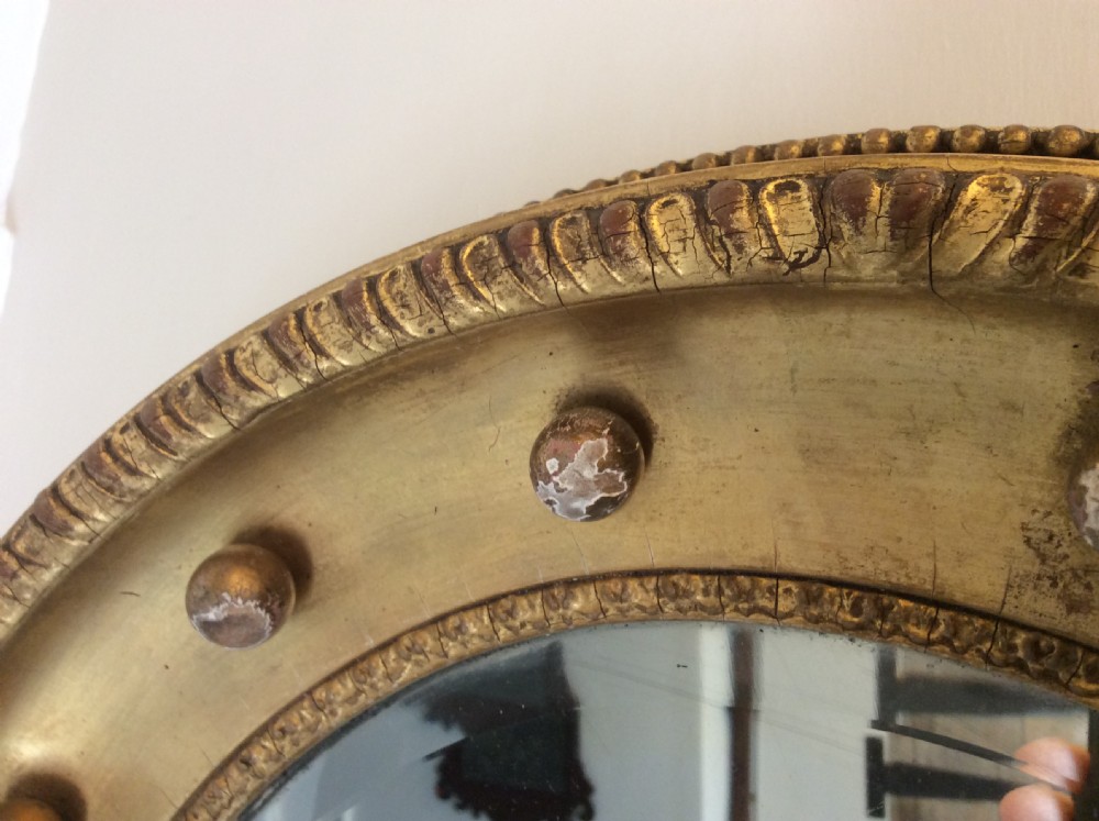 A 19th-century circular convex mirror featuring a gilded frame with decorative spherule accents. View VIII