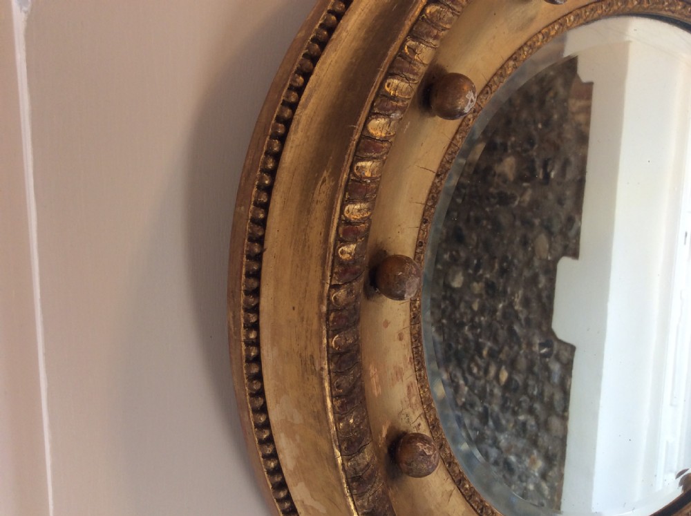 A 19th-century circular convex mirror featuring a gilded frame with decorative spherule accents. View IX