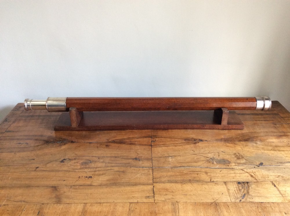 An 18th-century nine-sided mahogany and brass telescope resting on a matching wooden presentation stand.