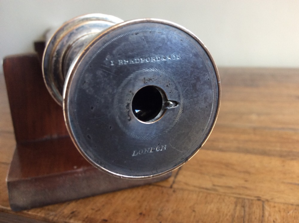 An 18th-century nine-sided mahogany and brass telescope resting on a matching wooden presentation stand. View V