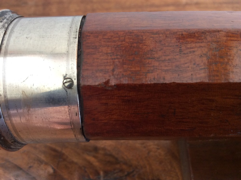 An 18th-century nine-sided mahogany and brass telescope resting on a matching wooden presentation stand. View X