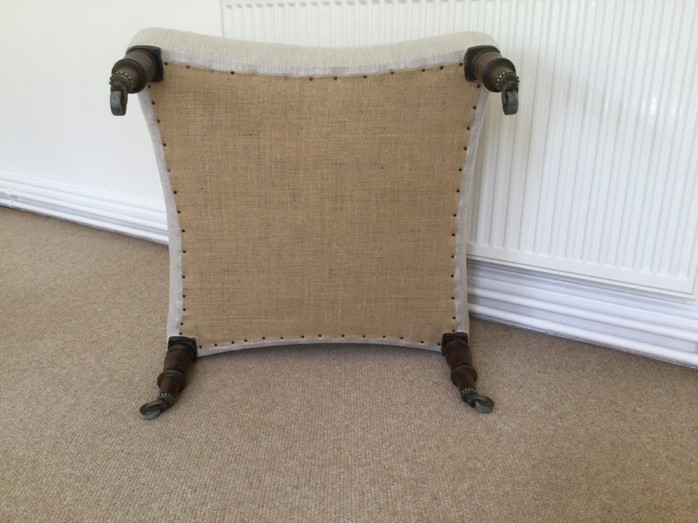 A 19th-century French upholstered footstool featuring cream linen fabric and turned wooden legs fitted with brass castors. View VII