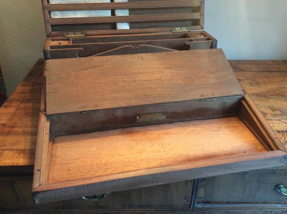 A rectangular warm brown teak campaign writing box featuring flush brass strapwork on the corners and a central decorative brass keyhole escutcheon. View XIII