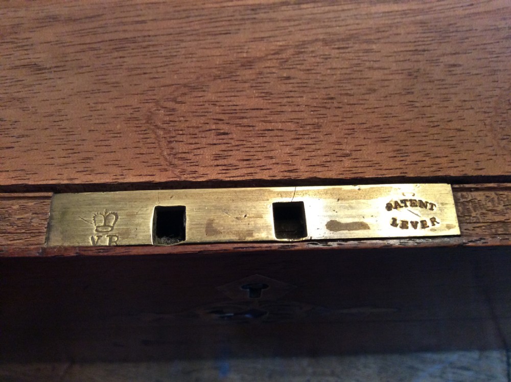 A rectangular warm brown teak campaign writing box featuring flush brass strapwork on the corners and a central decorative brass keyhole escutcheon. View XIV