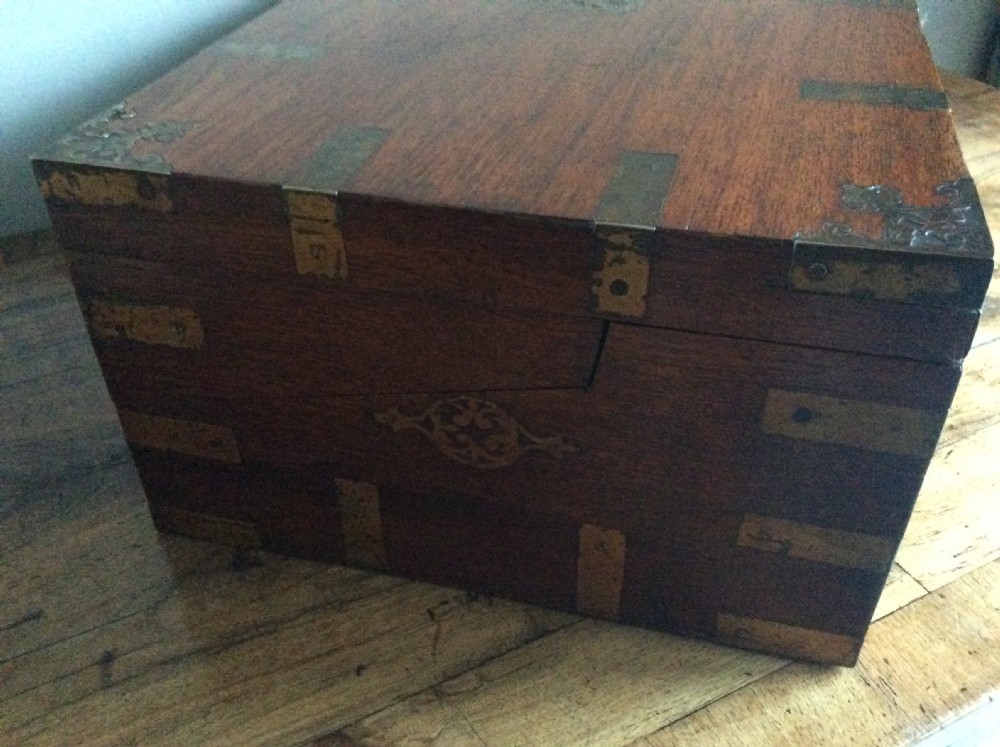 A rectangular warm brown teak campaign writing box featuring flush brass strapwork on the corners and a central decorative brass keyhole escutcheon. View XIX