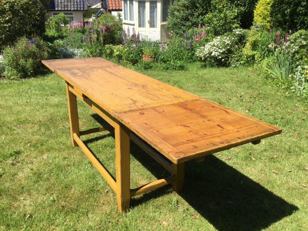 A rectangular warm pine farmhouse kitchen table featuring two end extension leaves supported by a sturdy square-legged stretcher base. View V