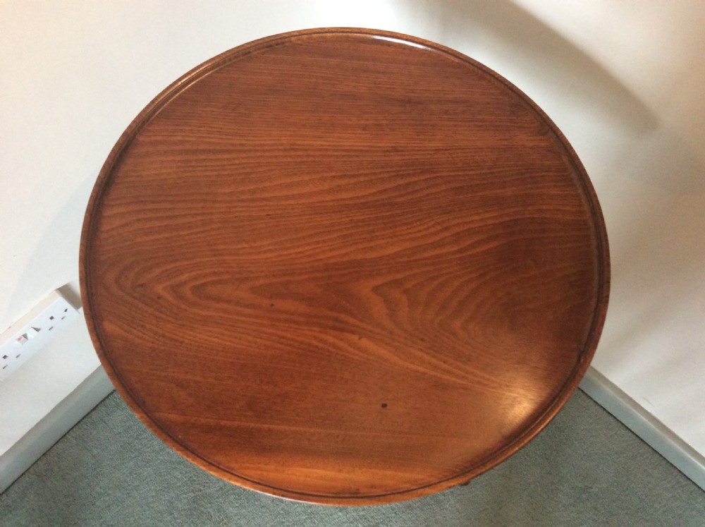 A George III mahogany tilt-top wine table with a circular dished top shown vertically above a turned column and tripod cabriole legs. View III