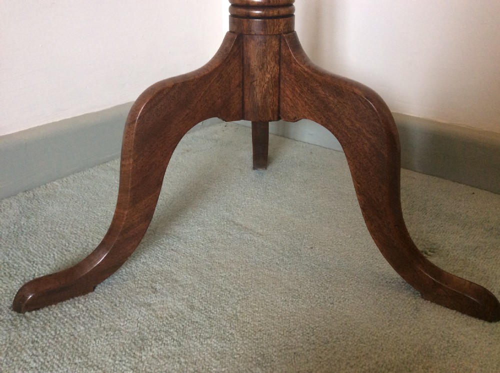 A George III mahogany tilt-top wine table with a circular dished top shown vertically above a turned column and tripod cabriole legs. View V