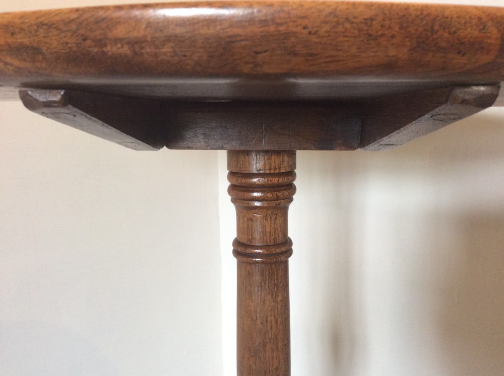 A George III mahogany tilt-top wine table with a circular dished top shown vertically above a turned column and tripod cabriole legs. View VIII