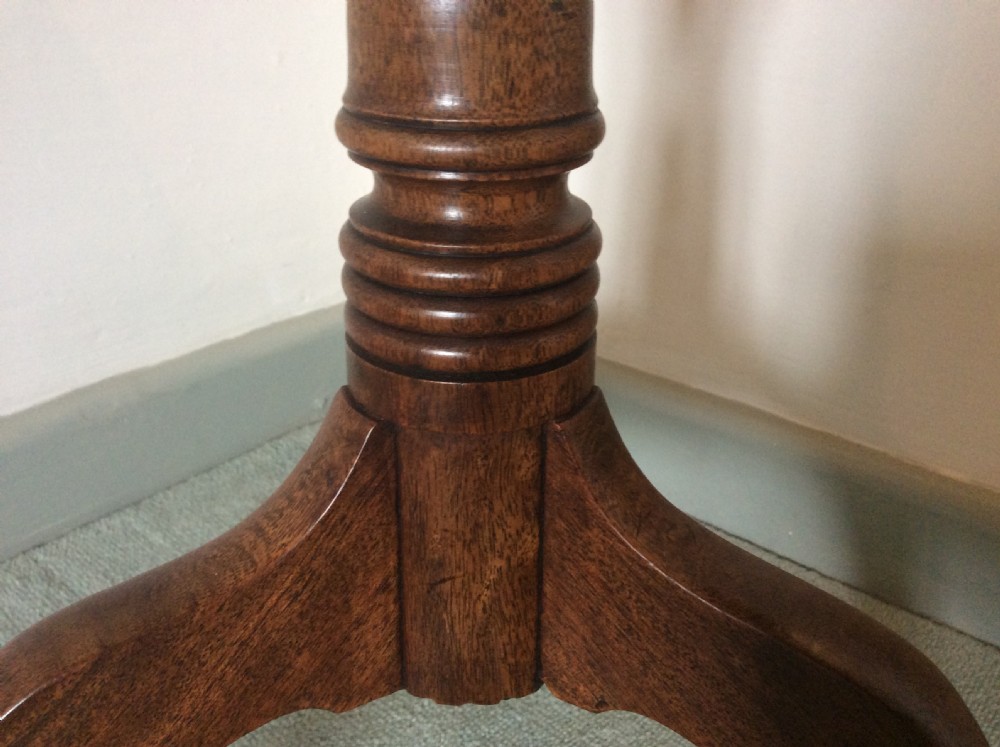 A George III mahogany tilt-top wine table with a circular dished top shown vertically above a turned column and tripod cabriole legs. View IX