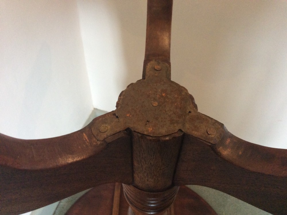 A George III mahogany tilt-top wine table with a circular dished top shown vertically above a turned column and tripod cabriole legs. View XIII