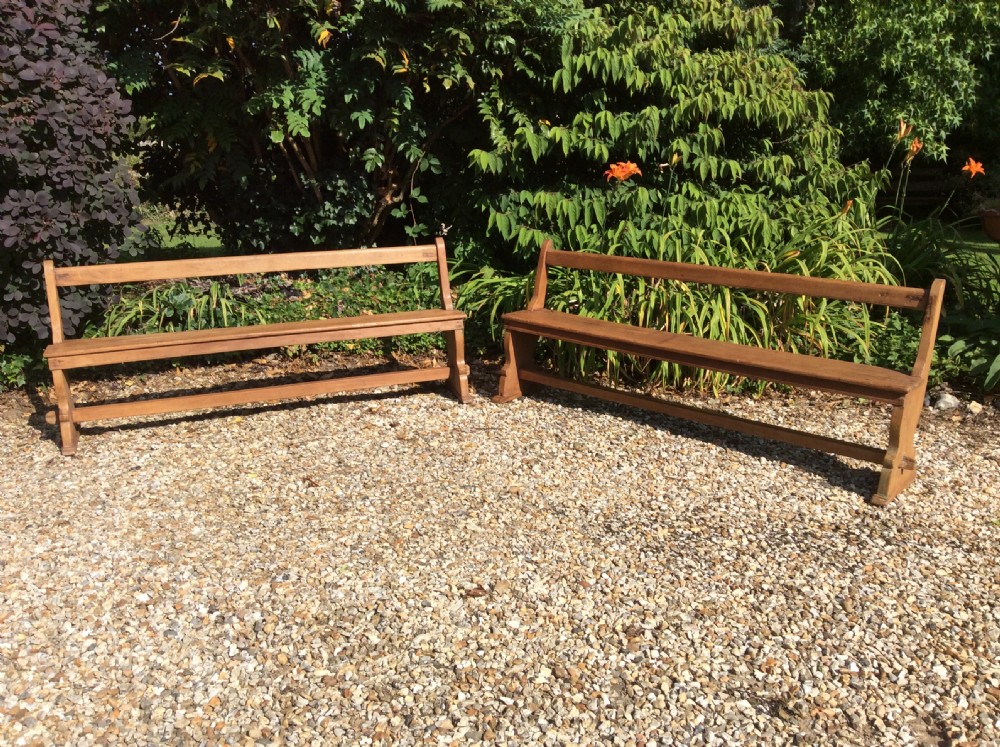A pair of matching warm brown timber benches featuring low backrests, shaped side supports, and lower stretchers.