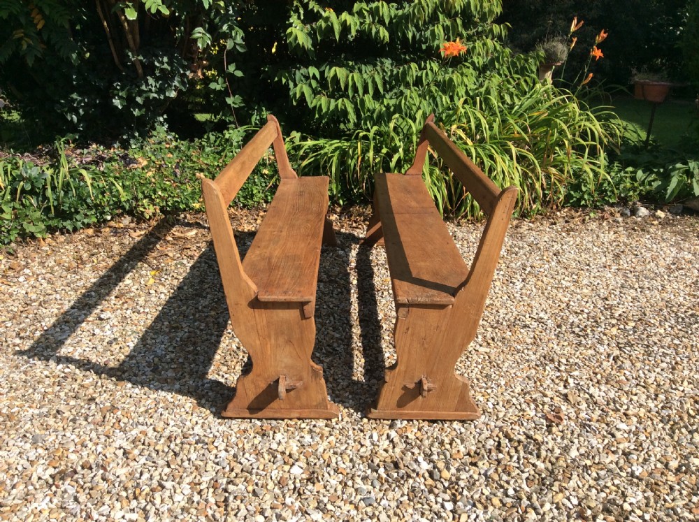 A pair of matching warm brown timber benches featuring low backrests, shaped side supports, and lower stretchers. View II