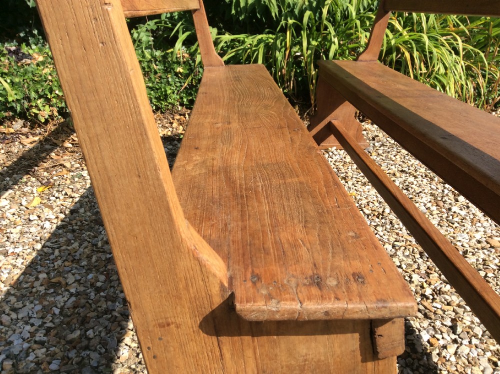 A pair of matching warm brown timber benches featuring low backrests, shaped side supports, and lower stretchers. View IV