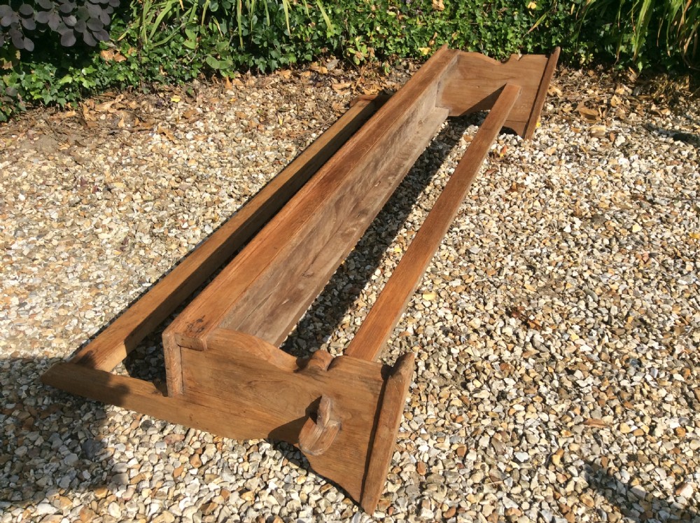 A pair of matching warm brown timber benches featuring low backrests, shaped side supports, and lower stretchers. View IX