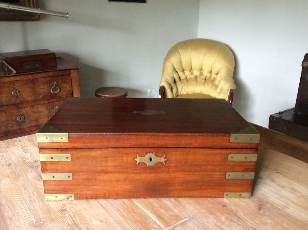 A rectangular mahogany campaign writing slope with flush brass corner brackets, brass straps, and a decorative brass keyhole escutcheon. View II