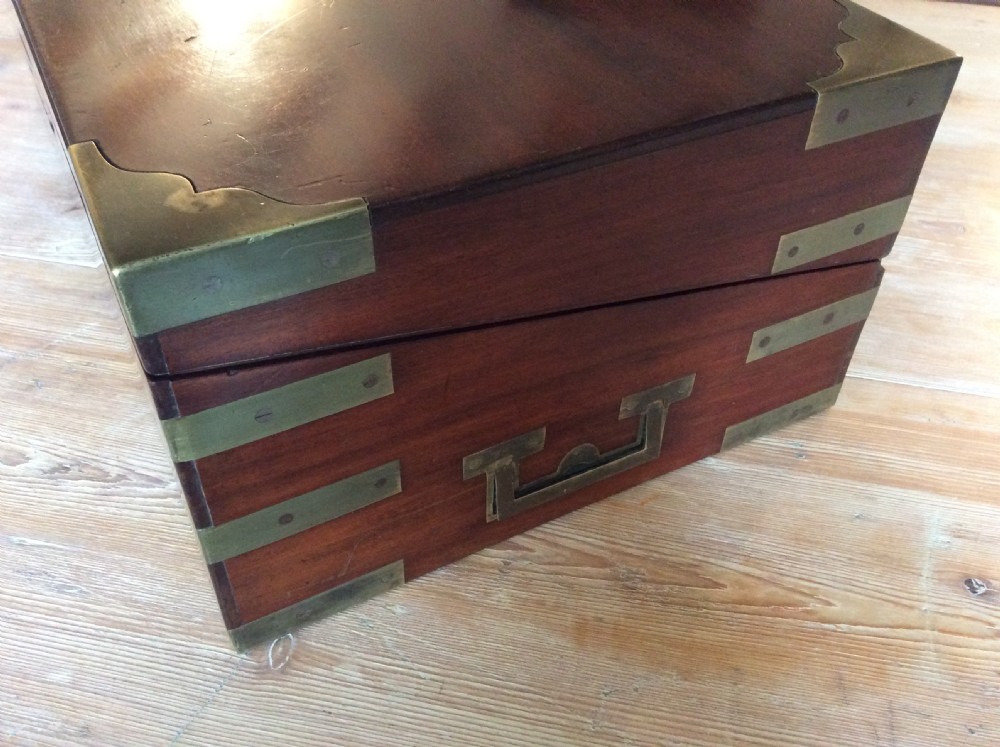 A rectangular mahogany campaign writing slope with flush brass corner brackets, brass straps, and a decorative brass keyhole escutcheon. View VI