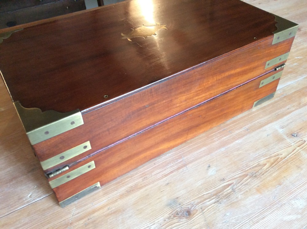 A rectangular mahogany campaign writing slope with flush brass corner brackets, brass straps, and a decorative brass keyhole escutcheon. View VII