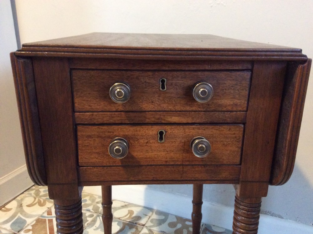 A 19th-century mahogany work table featuring two drawers with circular knobs, double drop leaves, and slender turned legs on brass castors. View II