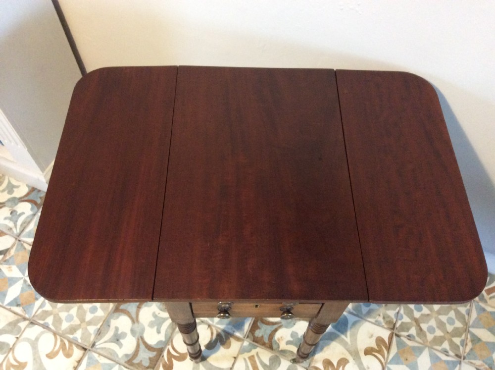 A 19th-century mahogany work table featuring two drawers with circular knobs, double drop leaves, and slender turned legs on brass castors. View V
