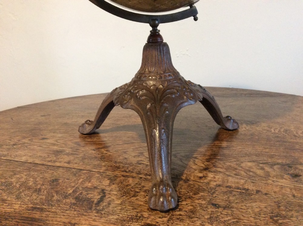 A printed paper terrestrial globe mounted on an ornate cast iron tripod base with a metal semi-meridian arm. View III