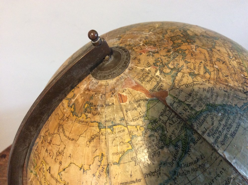 A printed paper terrestrial globe mounted on an ornate cast iron tripod base with a metal semi-meridian arm. View IV