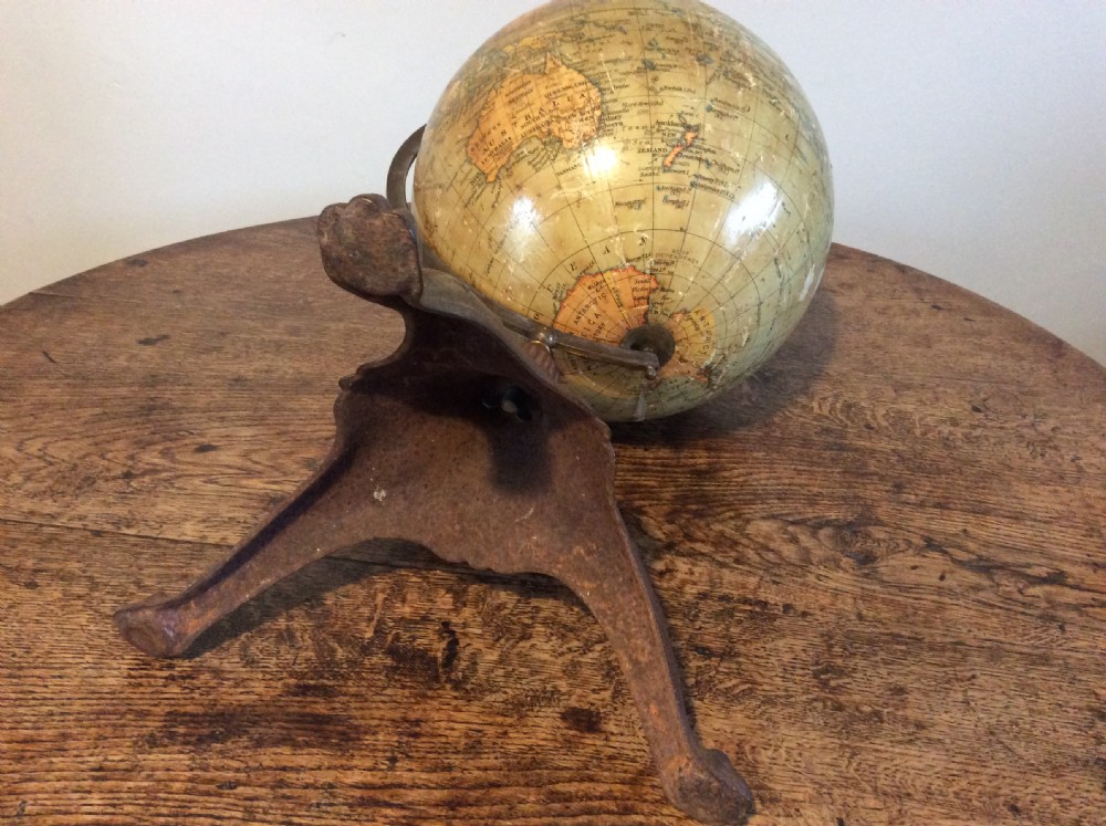 A printed paper terrestrial globe mounted on an ornate cast iron tripod base with a metal semi-meridian arm. View V