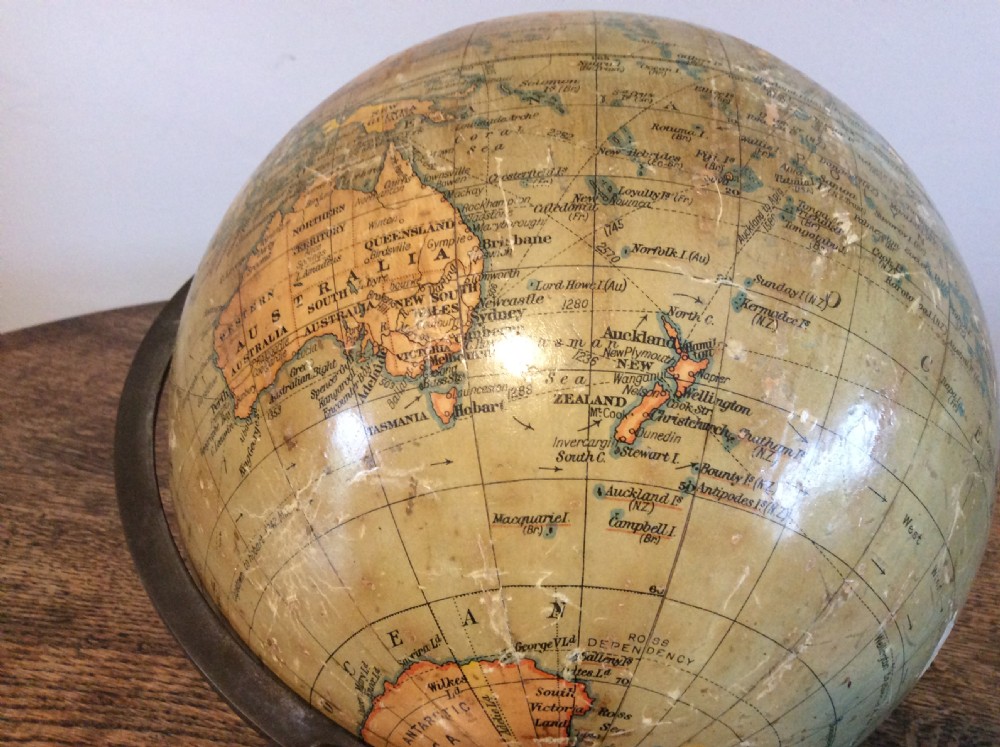A printed paper terrestrial globe mounted on an ornate cast iron tripod base with a metal semi-meridian arm. View VI