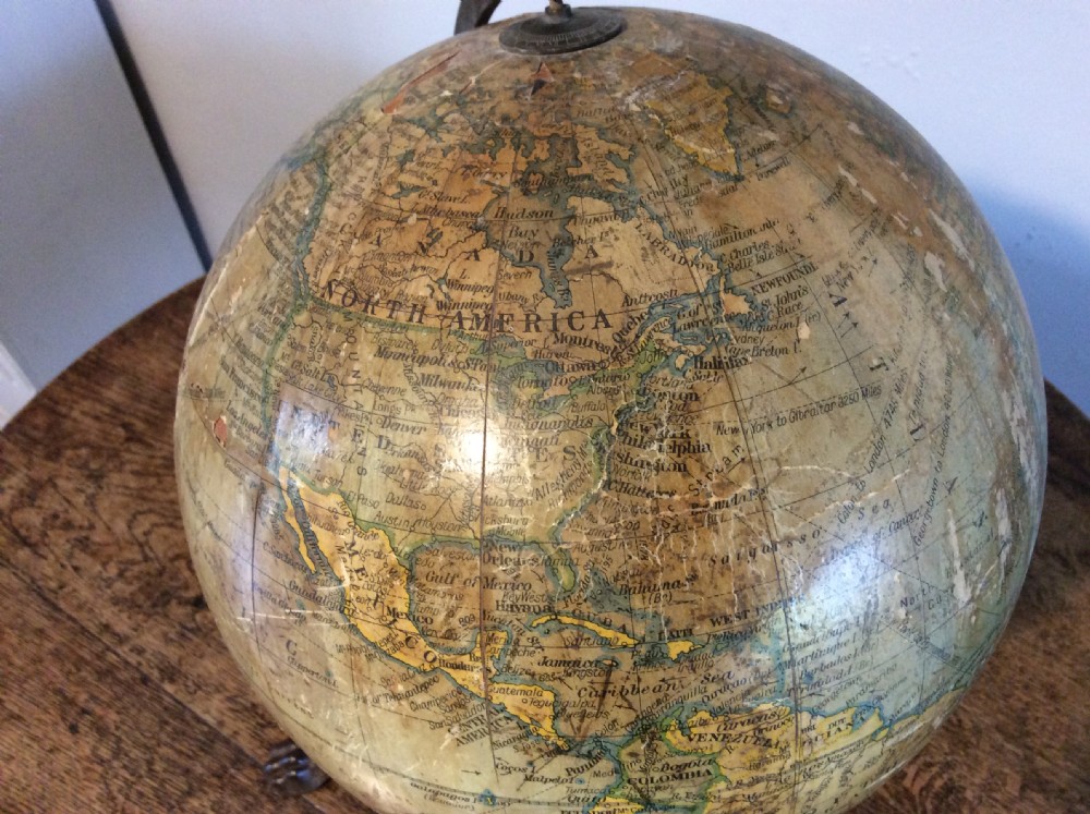 A printed paper terrestrial globe mounted on an ornate cast iron tripod base with a metal semi-meridian arm. View VII