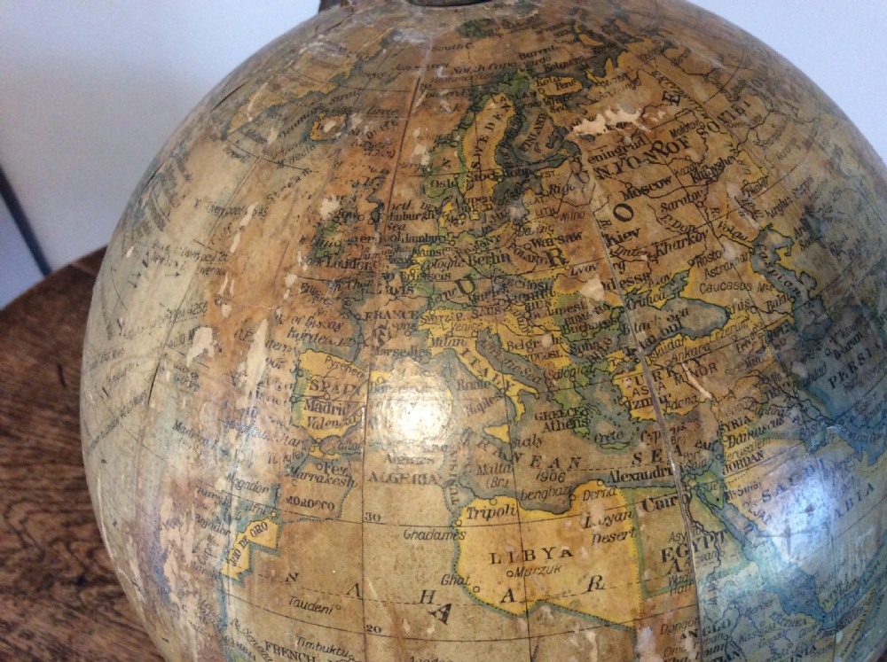 A printed paper terrestrial globe mounted on an ornate cast iron tripod base with a metal semi-meridian arm. View VIII