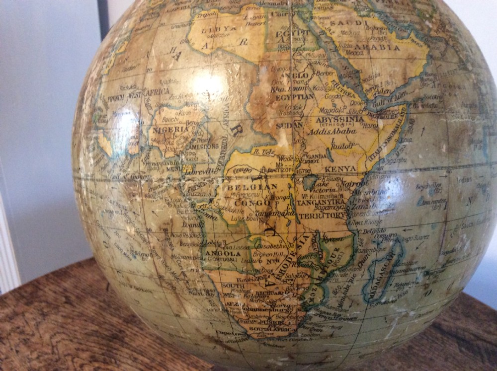 A printed paper terrestrial globe mounted on an ornate cast iron tripod base with a metal semi-meridian arm. View IX
