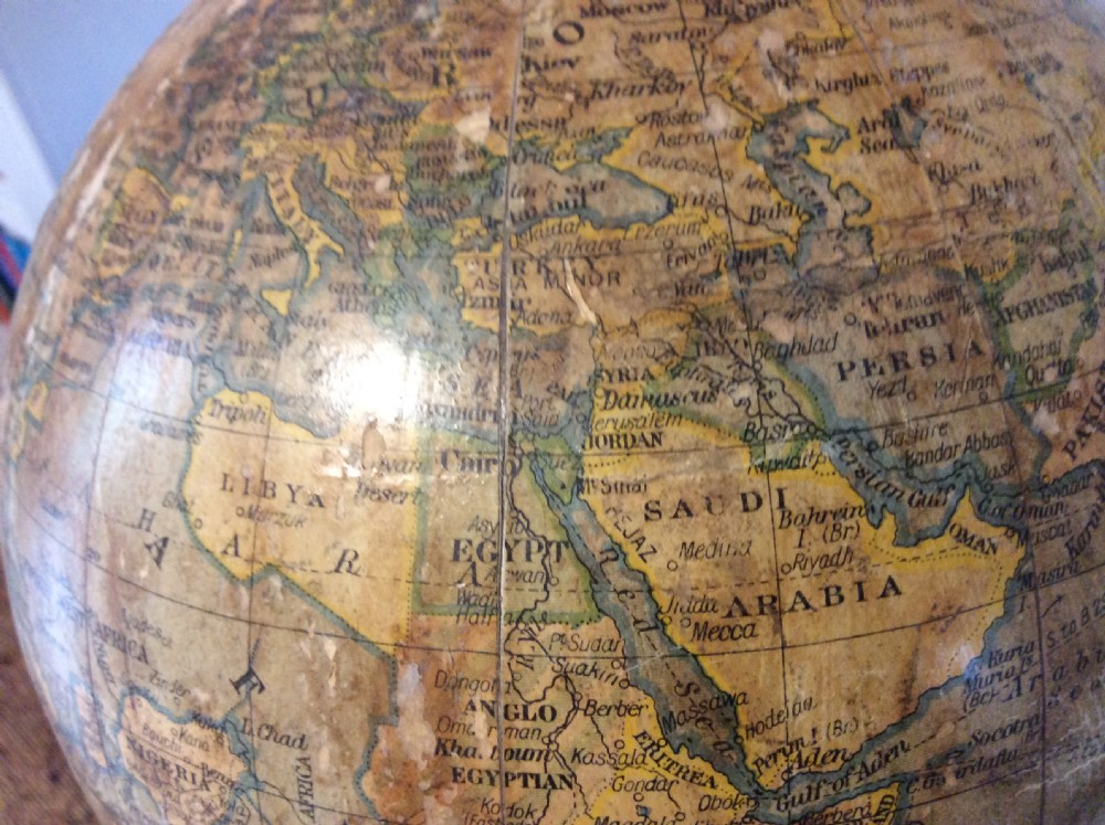 A printed paper terrestrial globe mounted on an ornate cast iron tripod base with a metal semi-meridian arm. View XII
